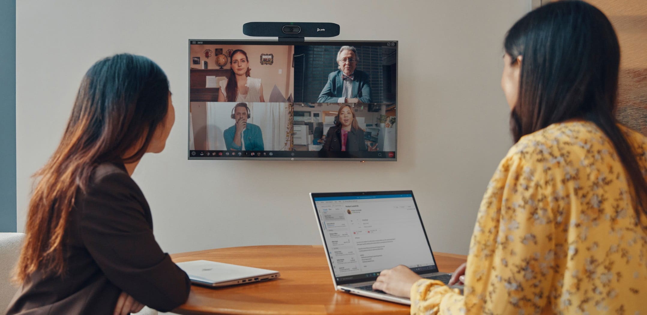 Two people in small meeting room using Poly Studio R30 video bar during video conferencing call​